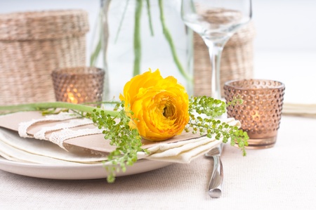 festive dining table setting with yellow-orange flowers ranunkulus