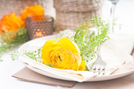 festive dining table setting with yellow-orange flowers ranunkulusの写真素材