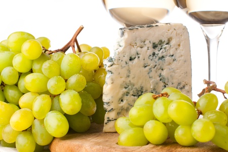 Blue cheese and a bunch of white grapes on a wooden boardの写真素材