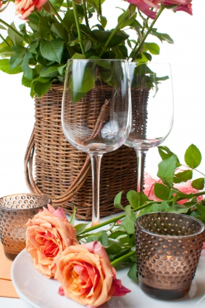 Festive table setting with roses and candles in shades of orange on a white backgroundの写真素材
