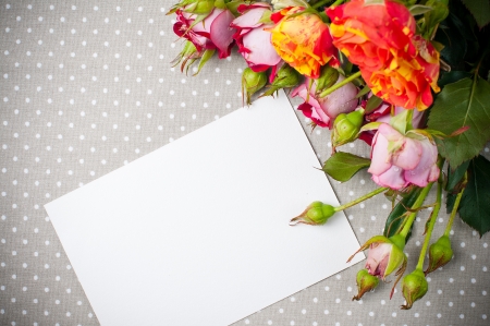 Bouquet of roses and white cardboard on a gray linen fabric closeupの写真素材