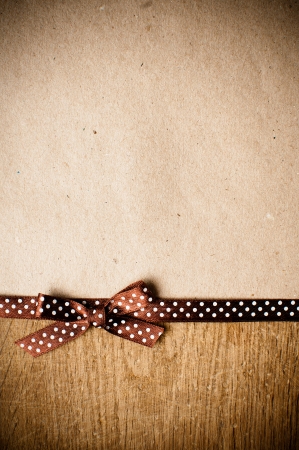 Wooden background with brown polka-dot ribbon and bow on brown kraft paperの写真素材