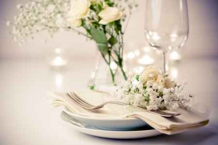 Festive table setting with roses in bright colors and vintage crockery on a beige backgroundの写真素材