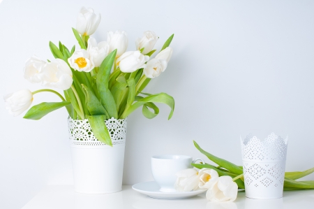 Home decoration, fresh white tulips in a vase and a cup on a white table, close-upの写真素材
