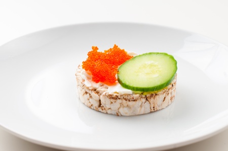 Appetizers with red fish, herbs, cucumber and red caviar on a white plate, close-upの写真素材