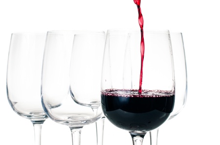 Wine-tasting, red wine pouring into empty glass closeup on a white background, isolated