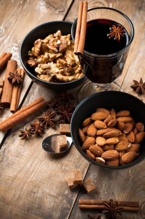 A glass of hot mulled wine, spices, cinnamon, star anise, brown sugar and nuts on a wooden boardの写真素材