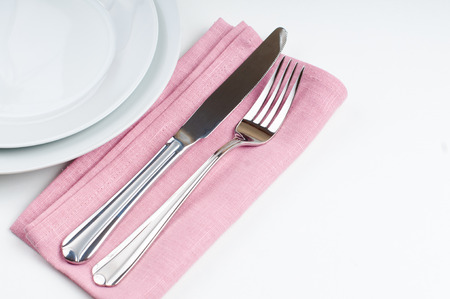 Shiny new cutlery, silverware and a napkin close-up on white background