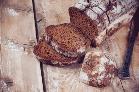 A loaf of fresh rustic wholemeal rye bread, sliced â€‹â€‹on a wooden board, rural food...