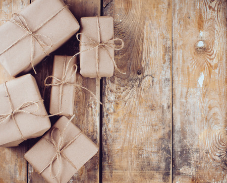 Several gift boxes, postal parcels wrapped in brown kraft paper tied with a rope on a wooden board