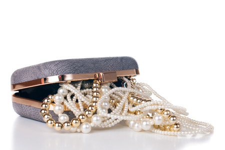 Jewelry of gold and white pearls in the open female handbag on a white background, isolated.の写真素材