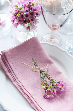 Festive wedding table setting with pink flowers, napkins, vintage cutlery, glasses and candles, bright summer table decor.の写真素材
