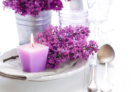 Festive wedding table setting with lilac flowers, candles, vintage cutlery, glasses and dishesの写真素材