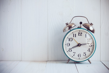 Big old vintage alarm clock with bells, painted white wooden background