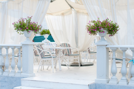 Summer cafe terrace with elegant furniture, flowers and canopy in beige and blue tonesの写真素材