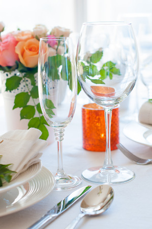 Festive table setting with colorful flowers, cutlery, candles. Wedding table decoration, wineglasses.の写真素材