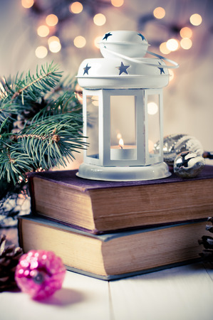 Vintage Christmas decor, old Christmas decorations, lanterns, garlands and spruce branches on a stack of booksの写真素材