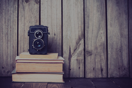 Vintage medium format camera and a stack of books on a wooden board, hipster styleの写真素材