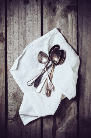 Old vintage cupronickel spoons and napkin on old wooden board, silverwareの写真素材