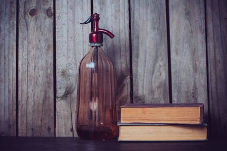 Old siphon and vintage books on wooden backgroundの写真素材