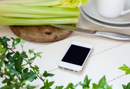 White smartphone on white wooden kitchen tableの写真素材