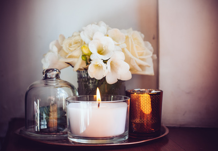Bouquet of white flowers in a vase, candles on vintage copper tray, wedding home decor on a tableの写真素材