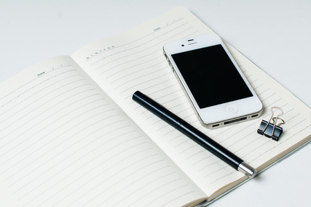 Business office objects: smartphone, notebook and pen on a white background