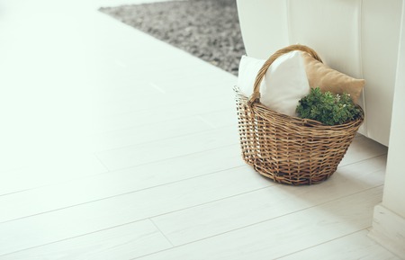 Wicker basket with pillows and green home plant on a floor by the sofa, modern home interior decorの写真素材