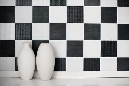 Two ceramic vases on a table near the black-and-white wallの写真素材