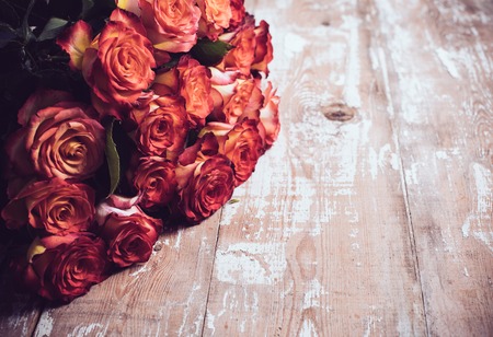 A large bouquet of fresh roses on an old wooden board, vintage backgroundの写真素材
