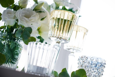 Two glasses of champagne and white flowers, candles on white table. の写真素材