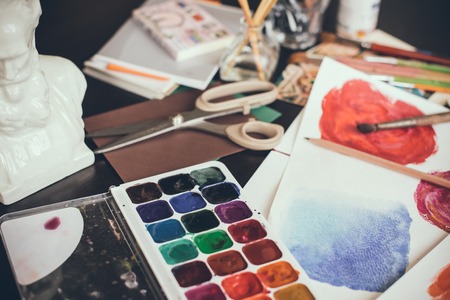 Mess in the the artist's studio, watercolor paints, brushes and sketches, palette and painting tools. Designer's working place, hipster style.の写真素材