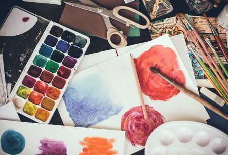 Mess in the the artist's studio, watercolor paints, brushes and sketches, palette and painting tools. Designer's working place, hipster style.の写真素材