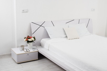 Interior of white bedroom, new linens on the bed in the hotel roomの写真素材