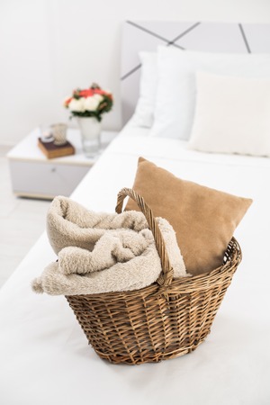 Interior of white bedroom, new linens on the bed, cozy home. Wicker basket and pillows closeup.の写真素材