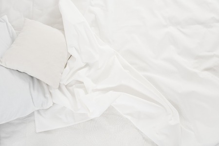 New snow-white bed, pillows and crumpled sheets, white linen cloth, white abstract background.の写真素材