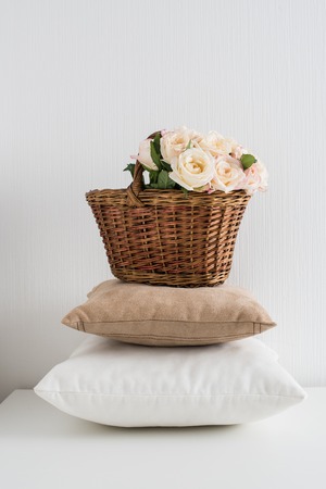 Basket with flowers on a pile of pillows by the white wall, a cozy home decorの写真素材