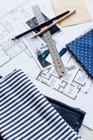 Interior designer's working table, an architectural plan of the house, a color palette, furniture and fabric samples in blue color. Drawings and plans for house decoration.の写真素材