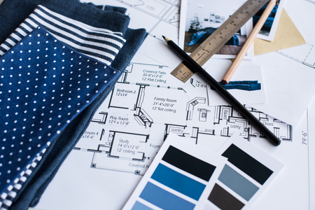 Interior designer's working table, an architectural plan of the house, a color palette, furniture and fabric samples in blue color. Drawings and plans for house decoration.の写真素材
