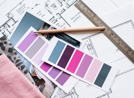 Interior designer's working table, an architectural plan of the house, a color palette, furniture and fabric samples in grey and pink color. Drawings and plans for house decoration.の写真素材