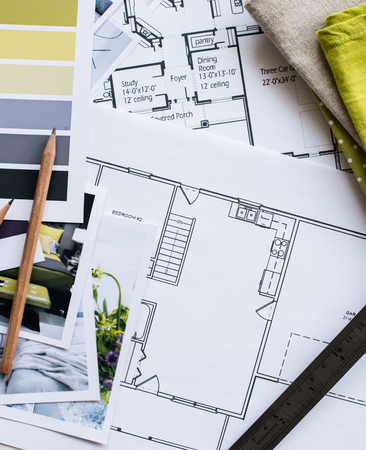 Interior designer's working table, an architectural plan of the house, a color palette, furniture and fabric samples in yellow and grey color. Drawings and plans for house decoration.の写真素材