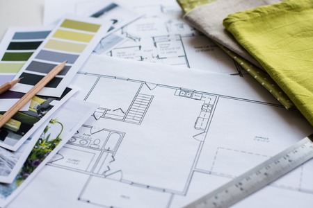 Interior designer's working table, an architectural plan of the house, a color palette, furniture and fabric samples in yellow and grey color. Drawings and plans for house decoration.の写真素材