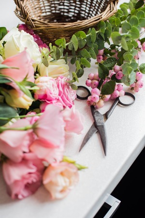 Fresh flowers, leaves, and tools to create a bouquet on a table, florist's workplace.の写真素材
