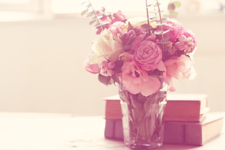 Elegant bouquet of pink flowers and ancient books on a tabke with backlight. Vintage decor.の写真素材