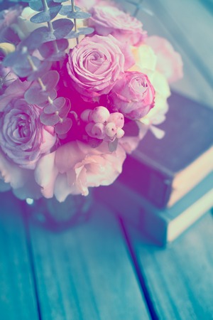 Elegant bouquet of pink flowers and ancient books on an old wooden board with copy space. Vintage...