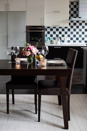 Dining table set with flowers, candles and glasses in the interior of modern kitchenの写真素材