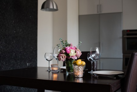 Dining table set with flowers, candles and glasses in the interior of modern kitchenの写真素材
