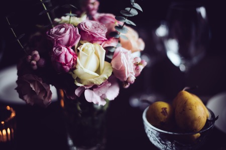 Bouquet of pink flowers on a table set for dinner with candles, close-up