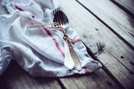 Vintage cutlery on a linen napkin on an old wooden board backgroundの写真素材