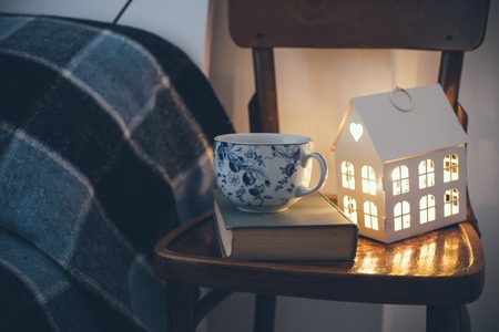 Cozy vintage bedroom interior closeup, cup of tea and a night light on a chair. Home interior decor with blue plaid and warm light.の写真素材